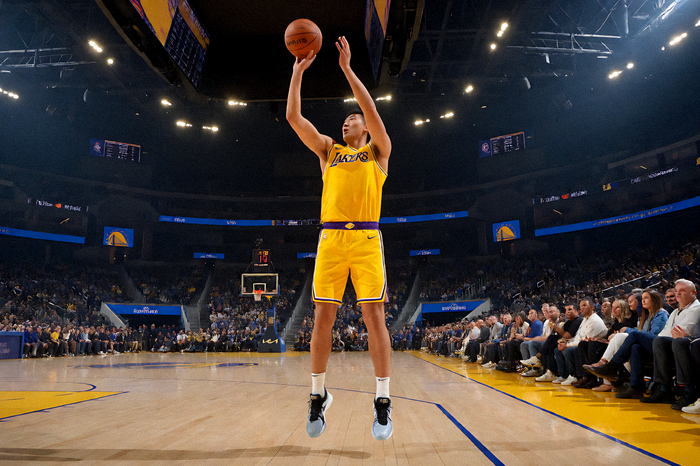 NBA常规赛湖人对阵勇士比赛中球员跳投瞬间，球馆内灯光璀璨气氛热烈