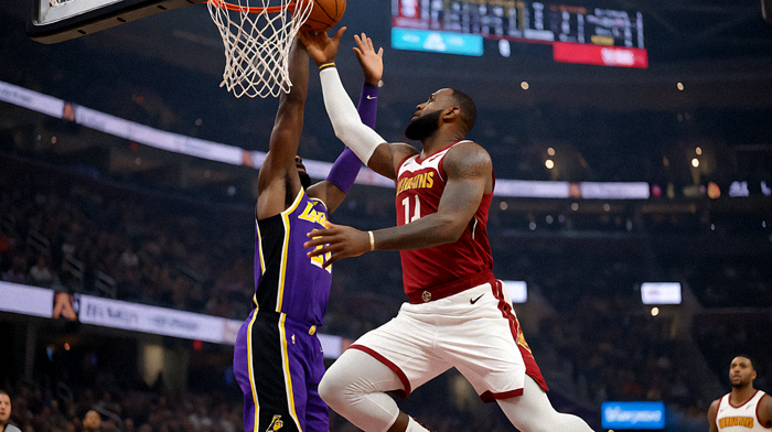 勒布朗·詹姆斯在NBA常规赛中突破上篮，防守者身穿湖人紫金球衣上前封盖